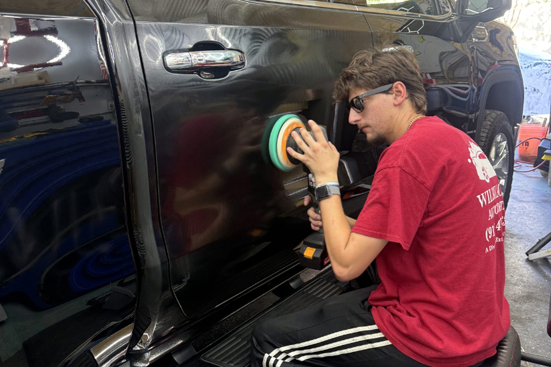 Detailer machine-polishing a black truck — paint correction Wilmington NC, swirl mark removal