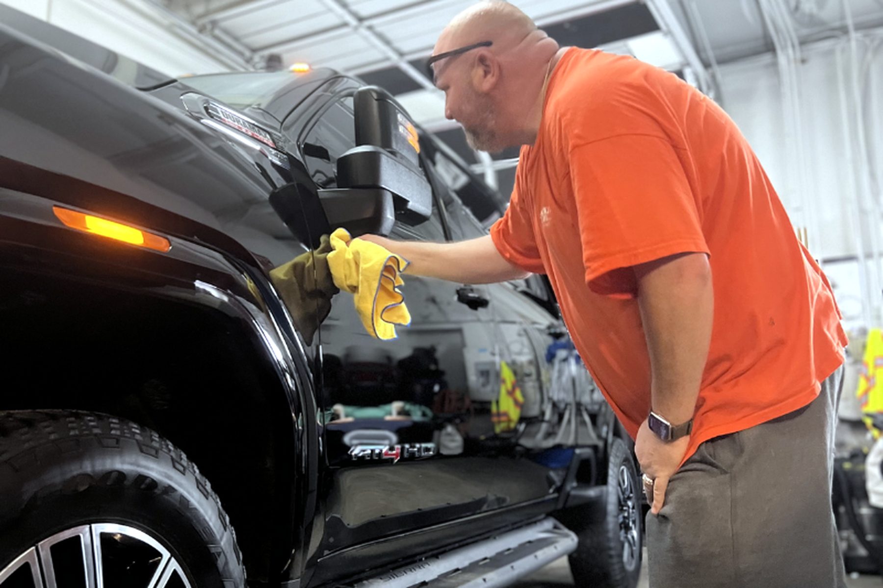 Wilmington Auto Detail technician wiping down a black work truck — fleet vehicle cleaning near me
