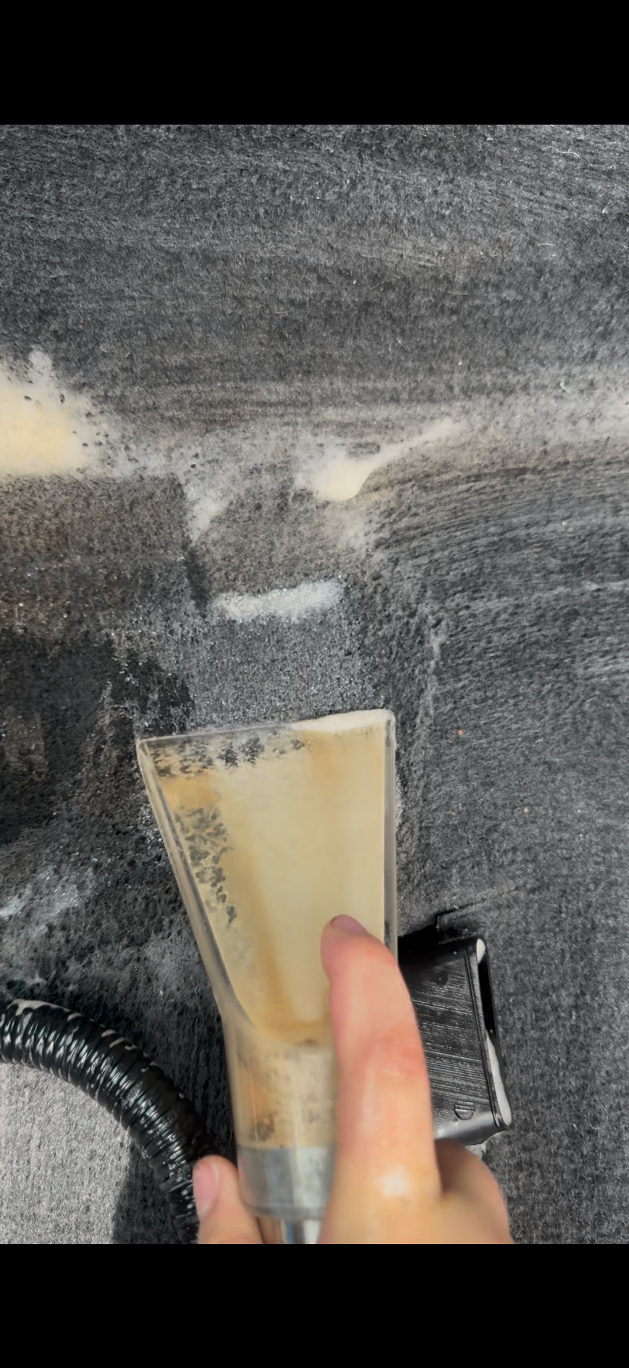 Detailer using a hot-water extractor wand to shampoo a car seat — interior shampooing Wilmington NC
